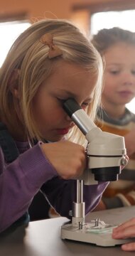 Education, science and child with microscope in class for development, knowledge or study. Kid, microbiology and learning with equipment in lab lesson, students and research experiment at school
