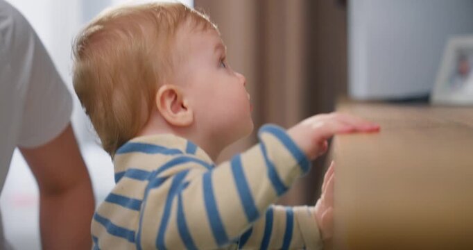 Curious toddler exploring surroundings by standing and touching surfaces indoors, showing early development and engagement with environment in a home setting