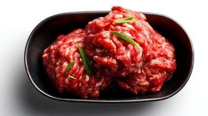 Obraz premium Three raw meatballs placed in a black bowl, garnished with green onions, representing fresh ingredients for culinary preparations and delicious homemade meals.