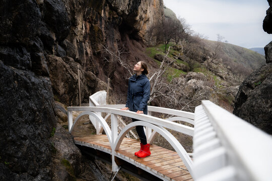 A young woman explores a rocky mountain canyon along an eco-friendly path, embarking on a solo travel and hiking adventure in a natural wilderness environment.
