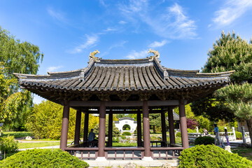 Obraz premium Front view of a beautiful pagoda against the blue sky and green trees in Chinese garden in a public park