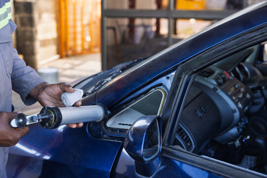 African Worker Repairing Car Window Frame with Sealant Gun replacement glass repair process