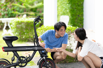 Obraz premium Asian Couple Cleaning and Repairing Electric Bike Together Outside Their Home