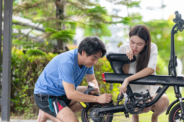 Obraz premium Asian Couple Cleaning and Repairing Electric Bike Together Outside Their Home
