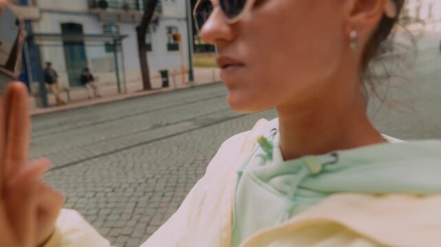 Woman in hoodie focused on her phone amidst city streets