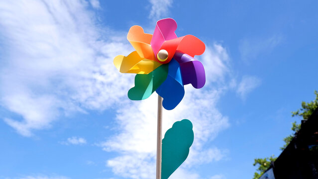 Colorful Rainbow Pinwheel Toy Against a Bright Blue Summer Sky