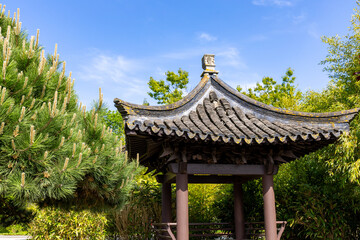 Fototapeta premium Angle view of a beautiful pagoda pavilion against the blue sky and green trees in Chinese garden in a public park