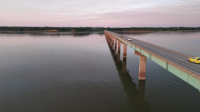 Aerial drone footage focusing on the wooden railing and deck structure of Mile Long Bridge at Saylorville Lake Iowa extending over calm still water at dusk near Des Moines