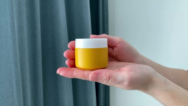 A woman holds a yellow jar for iodine ointment. Convenient and practical packaging allows you to quickly access the product. The importance of thoughtful design of medical products