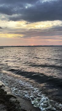 Scenic sea horizon with purple and pink sunset tones reflecting on calm water. Purple sunset over the sea with vibrant sky and colorful clouds, peaceful and romantic seascape. Vertical resolution.