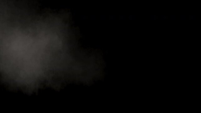 Realistic gray smoke cloud from an explosion dissipating on a black background.