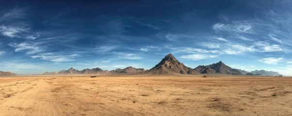 Vast panorama of a desert landscape under a vibrant, cloud-streaked blue sky, with distant mountains © Syahrul