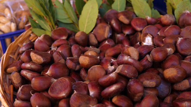 Plump glossy chestnuts on display at an Italian street market, an iconic autumn fruit deeply woven into Italian food culture, from roasted street snacks to festive seasonal desserts