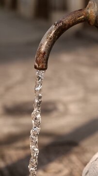 Vertical: A typical public fountain of Rome, known as Nasone, seen from above with clear water gently flowing from the spout