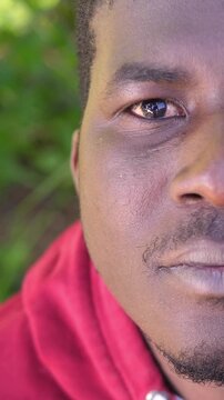 Vertical: Half face close up of a serious young African man opening his eyes, symbolizing awareness, realization and personal awakening in dramatic light.