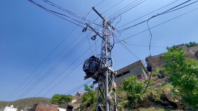 Pole‑mounted distribution transformer under overhead wires in Pakistan.