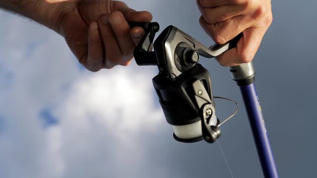 Dynamic Upward Shot of Fisherman Reeling In Line, Active Fishing Scene