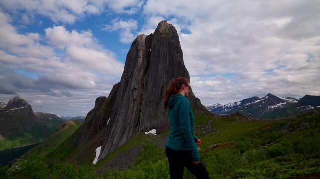Imposing Segla mountain in Fjordgard as female explorer hike past on trail