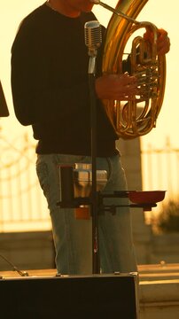 Musician tuba sunset playing brass instrument outdoors during golden hour performance with vintage microphone and warm lighting atmosphere