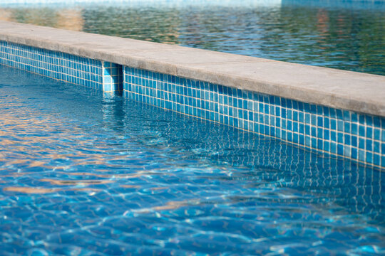 Close-up of clear blue swimming pool water with tiled edge and gentle ripples