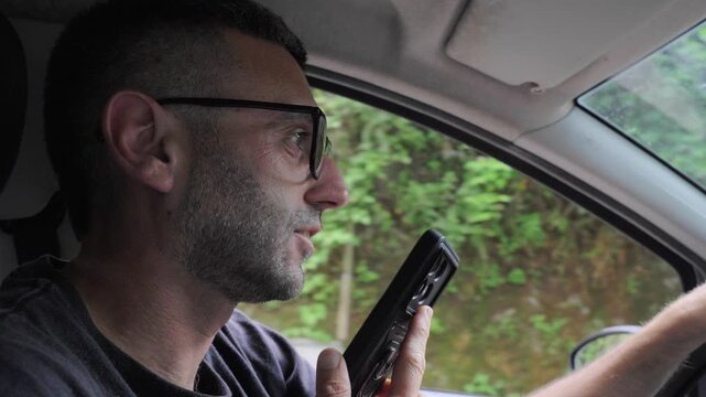 Ignoring basic traffic regulations, a young man records a voice note on his phone while driving, a widespread yet highly dangerous habit threatening road safety for everyone nearby.