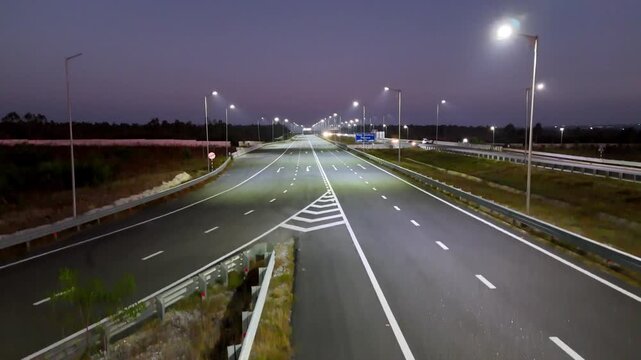 Drone shot capturing the Bengaluru&ndash;Chennai Expressway at evening time, featuring illuminated highway lanes, moving vehicles, and long symmetrical roadway patterns cutting across the night landscape.