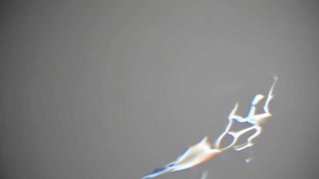 Abstract light reflections create dynamic patterns on a gray background, showcasing fluid motion and gradual transformation through three sequential frames of visual energy