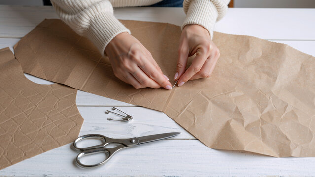 Hands pinning paper pattern for sewing project
