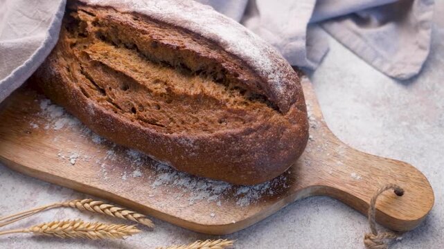 Freshly baked rye bread loaf resting on wooden board