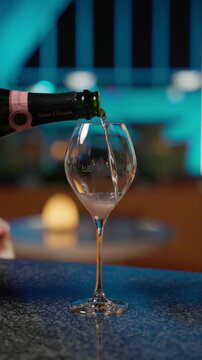 Champagne Being Poured into a Crystal Wine Glass at a Luxury Rooftop Bar with Teal Ambient Lighting, Bangkok, Thailand. 4K Vertical