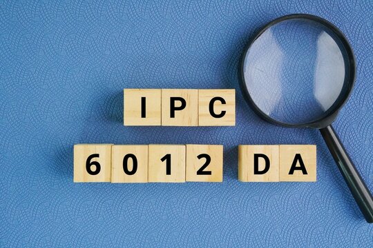 Wooden cube with words IPC-6012DA. Automotive Applications Addendum to IPC-6012D, which serves as the premier qualification and performance specification for rigid printed boards