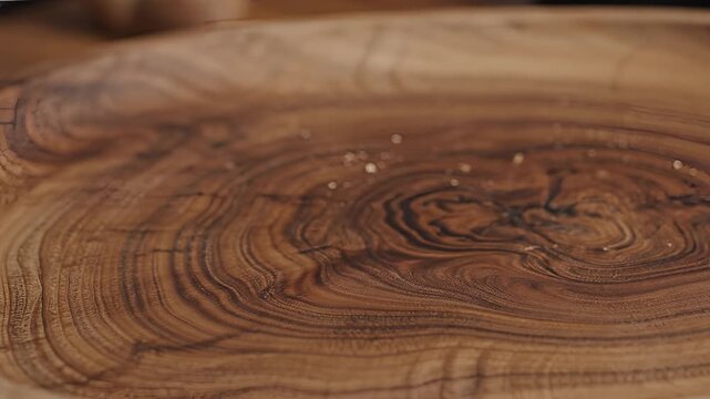 Closeup of a hand holding a rustic loaf of bread on a wooden cutting board.