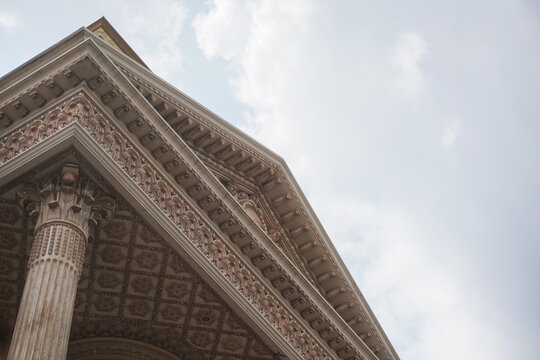 Architectural Detail of Ornate Building with Intricate Carvings and Cloudy Sky.