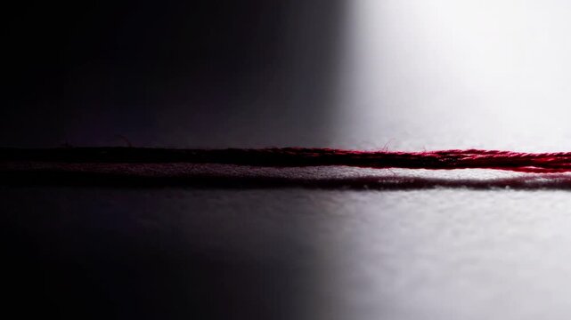 A close-up view of a thin red and black cord on a white surface
