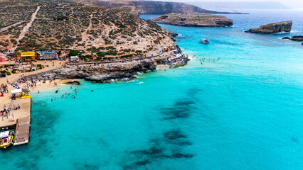 Landscape aerial drone shot of the blue lagoon beach and port in malta, comino island with green foliage and limestone rock and sandy beach busy with tourists in summer © STJMEDIA