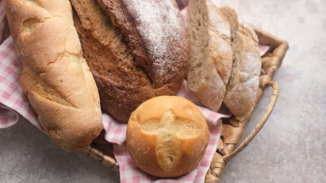 Assorted fresh bread, including loaves and rolls, resting in a basket on a rustic stone table