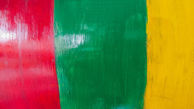Weathered painted wall with red yellow and green textured surface, distressed cracks and peeling paint details, ideal for Juneteenth themes, artistic backdrops, and abstract graphic backgrounds.