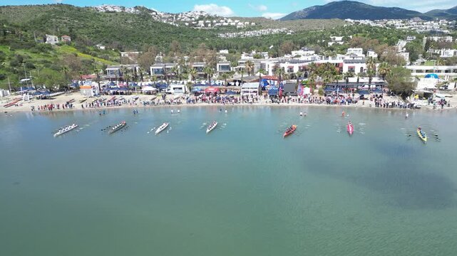 Aerial View of Professional Rowing Teams Competing in a Regatta near Scenic Coastal Town with Mountains. High quality 4k footage