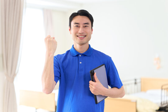 介護施設でガッツポーズをするアジア人男性介護士