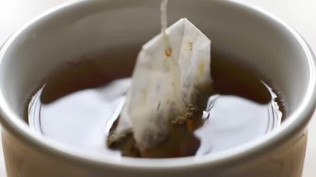 Close-up of a tea bag steeping in a cup of hot water.