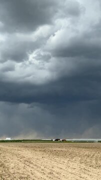 Dark storm clouds over sandy open landscape with strong wind and blowing dust ideal for dramatic weather footage, climate visuals and nature backgrounds