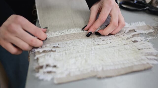 Close up of fabric layers being aligned and inspected, showing raw edges and fringe textures in a garment development process