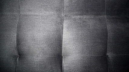 Naklejka premium Dark grey tufted fabric texture with quilted stitching pattern.