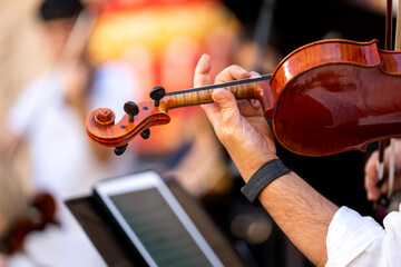 Musician's hand playing violin at an outdoor classical music concert © Alfonso Soler