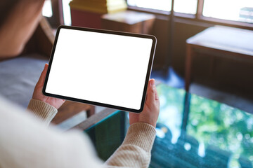 Naklejka na ściany i meble Mockup image of a woman holding digital tablet with blank white desktop screen in cafe