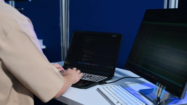 programmer hands typing code on laptop keyboard at night office