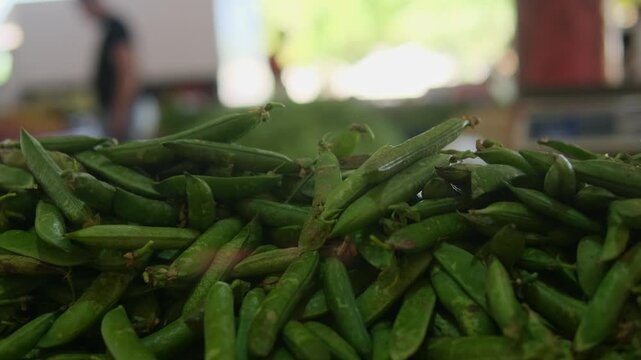 Young green peas at busy local market shallow depth of field authentic street shopping atmosphere and realistic everyday food lifestyle scene