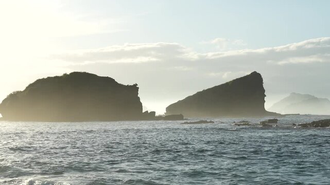 A giant sea stack rock on the coast of Papuma beach with beautiful ocean waves, a popular travel destination in East Java, Indonesia