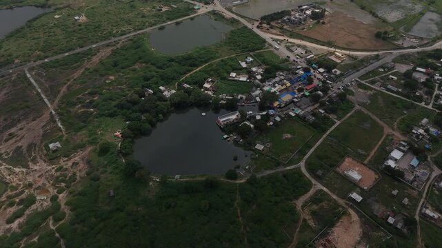 Top-down aerial view of the sacred Gopi Talav lake surrounded by lush green forest near Dwarka, Gujarat.