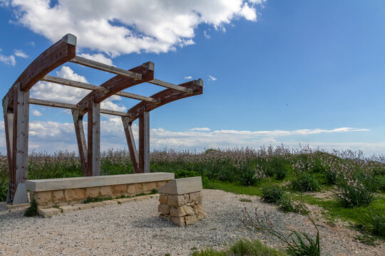 Wooden viewpoint canopy with stone bench on green hill overlooking Mediterranean sea . Wild asphodel flowers blooming in countryside near Kourion, Cyprus.